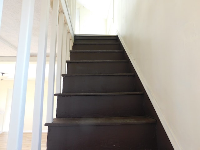 staircase with baseboards and wood finished floors