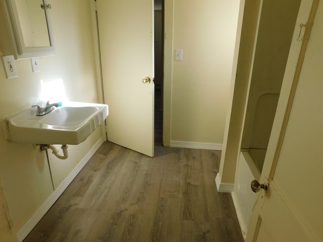 bathroom with a sink, baseboards, and wood finished floors