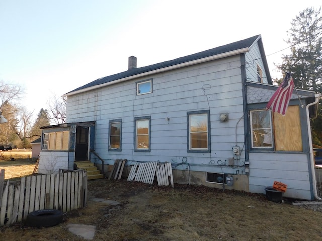 rear view of house featuring fence, a chimney, and entry steps