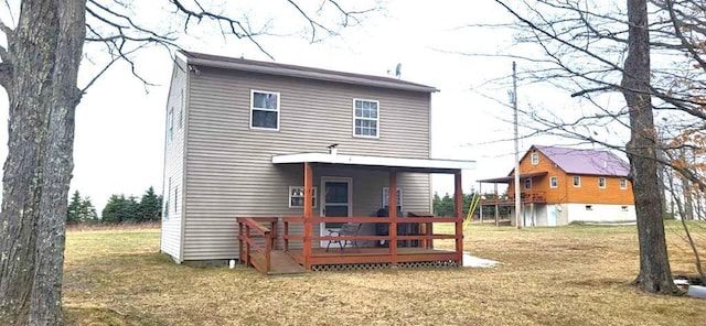 rear view of house with a wooden deck and a lawn