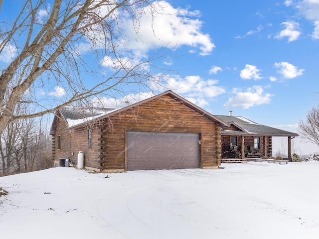 view of front facade featuring central AC, log exterior, and an attached garage