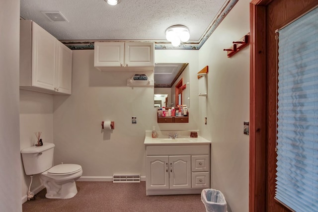 bathroom with a textured ceiling, vanity, and toilet