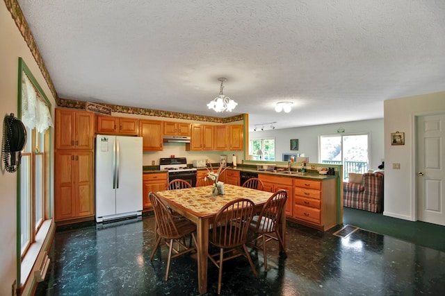 kitchen with sink, a notable chandelier, kitchen peninsula, a textured ceiling, and white appliances