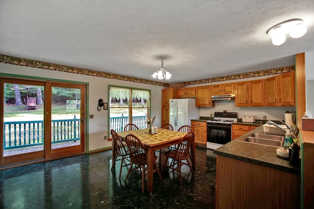 kitchen featuring white appliances, sink, a textured ceiling, decorative light fixtures, and a chandelier