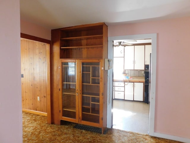 hall with carpet flooring and wooden walls