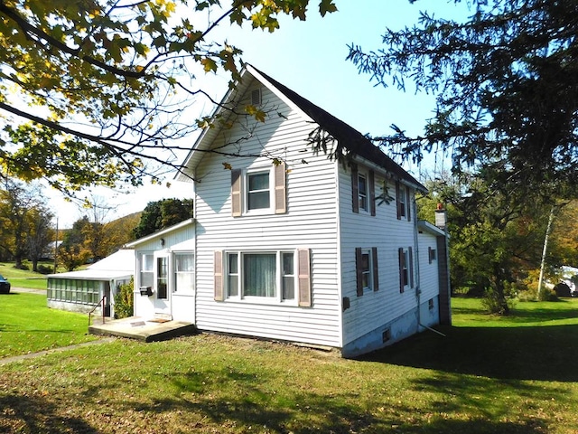 rear view of house with a lawn and a sunroom