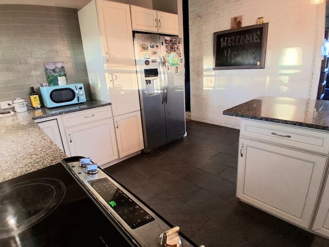 47 Alpine Dr, Athens, PA 18810 - kitchen with refrigerator with ice dispenser, white microwave, white cabinets, stove, and dark tile patterned flooring