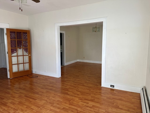 spare room with baseboard heating, ceiling fan, and wood-type flooring