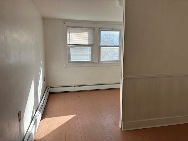 empty room featuring light wood-type flooring and a baseboard heating unit