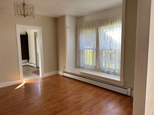 spare room featuring hardwood / wood-style flooring, a notable chandelier, and a baseboard radiator