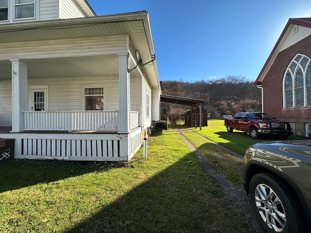 view of side of home with a yard and covered porch