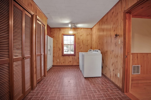 clothes washing area featuring washer and dryer and wooden walls