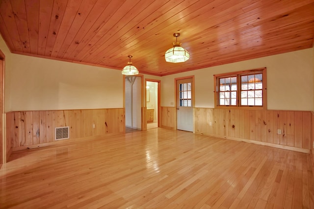 spare room with light hardwood / wood-style flooring, wood walls, and wood ceiling