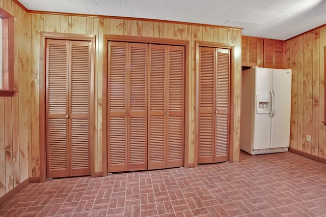 details featuring white refrigerator with ice dispenser and wooden walls