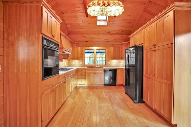 kitchen with hanging light fixtures, black appliances, light hardwood / wood-style floors, sink, and vaulted ceiling