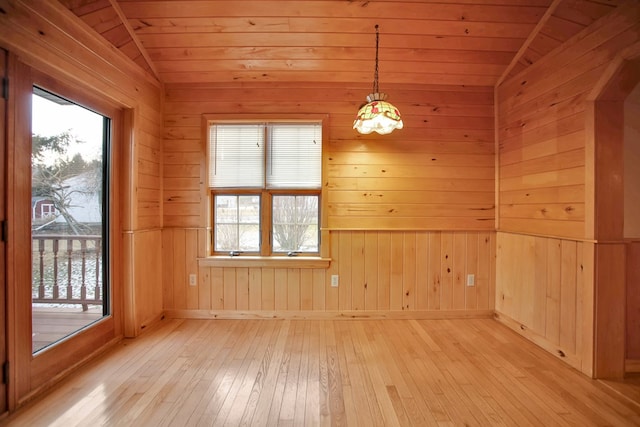 unfurnished dining area with light wood-type flooring, vaulted ceiling, wooden walls, and wooden ceiling