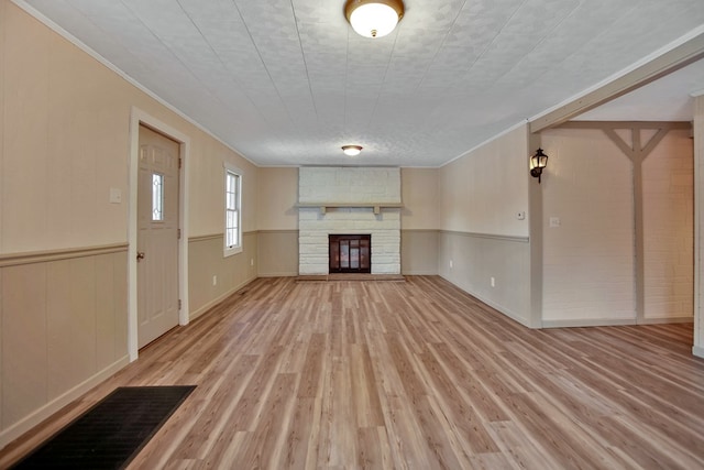 unfurnished living room with a fireplace, ornamental molding, and light wood-type flooring
