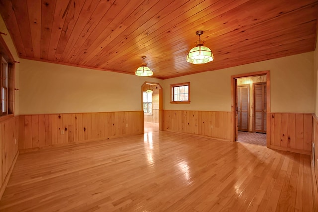 empty room with wooden walls, light hardwood / wood-style floors, and wooden ceiling