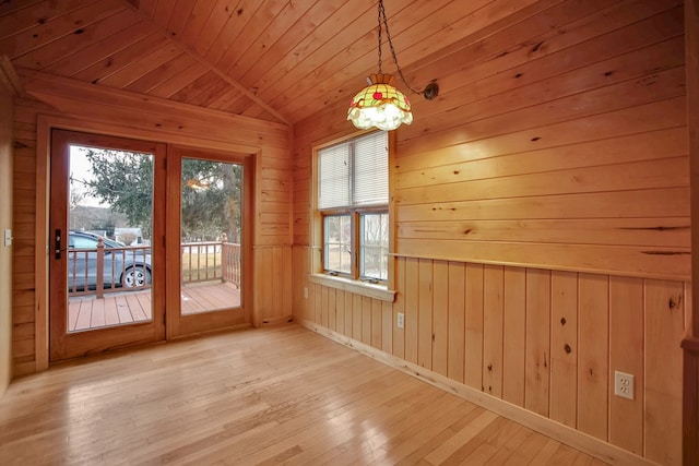 unfurnished dining area with wood walls, light wood-type flooring, vaulted ceiling, and wood ceiling