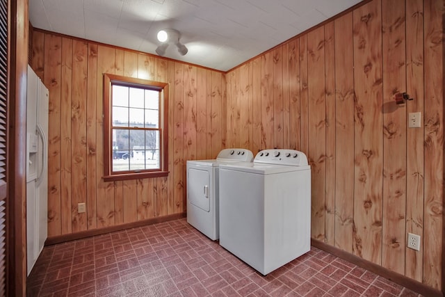 laundry room featuring wood walls, crown molding, and washing machine and clothes dryer