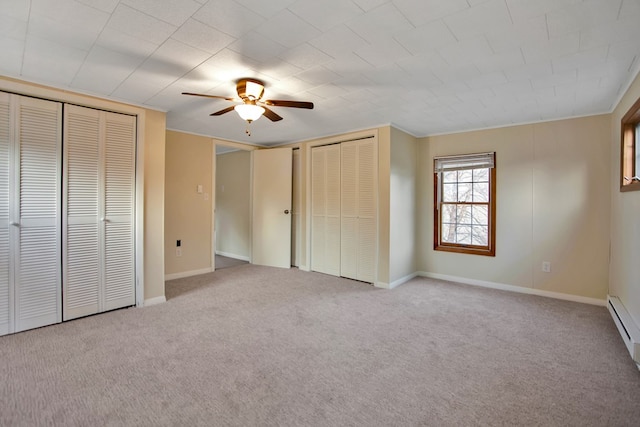 unfurnished bedroom with ceiling fan, multiple closets, light colored carpet, and crown molding