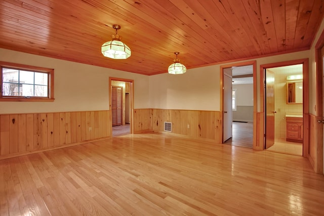 empty room with light hardwood / wood-style floors, wooden ceiling, and plenty of natural light