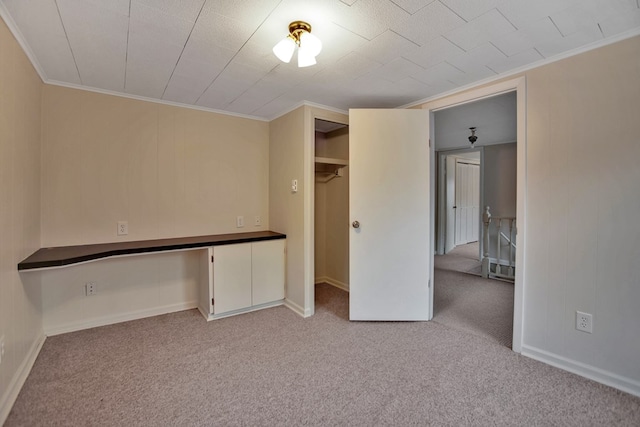 unfurnished bedroom with light carpet, crown molding, and built in desk