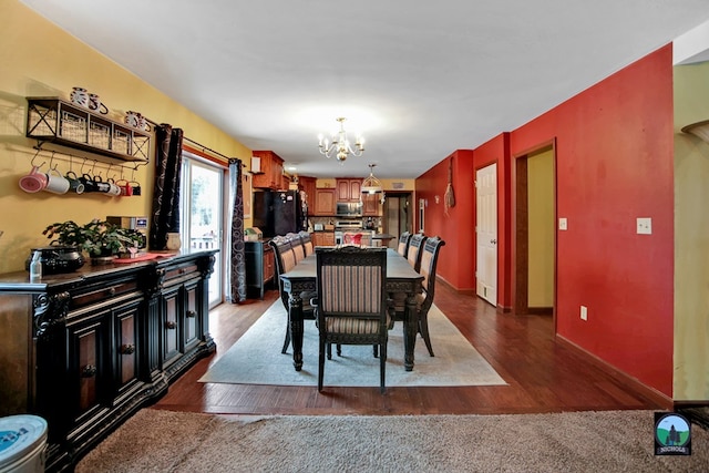 dining area with dark wood-type flooring and an inviting chandelier