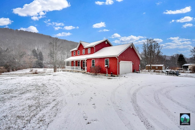 snow covered property with a garage and a porch