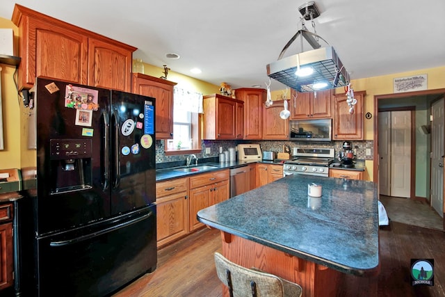 kitchen with sink, wood-type flooring, stainless steel appliances, and hanging light fixtures