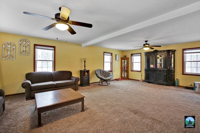 carpeted living room with ceiling fan and beamed ceiling