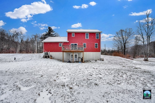 snow covered rear of property with a deck