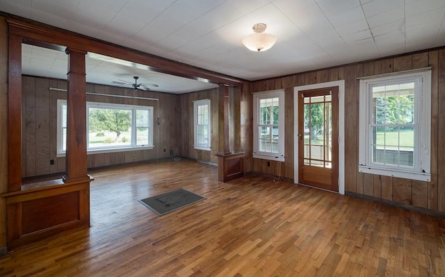 interior space with ornate columns, wooden walls, hardwood / wood-style floors, and ceiling fan