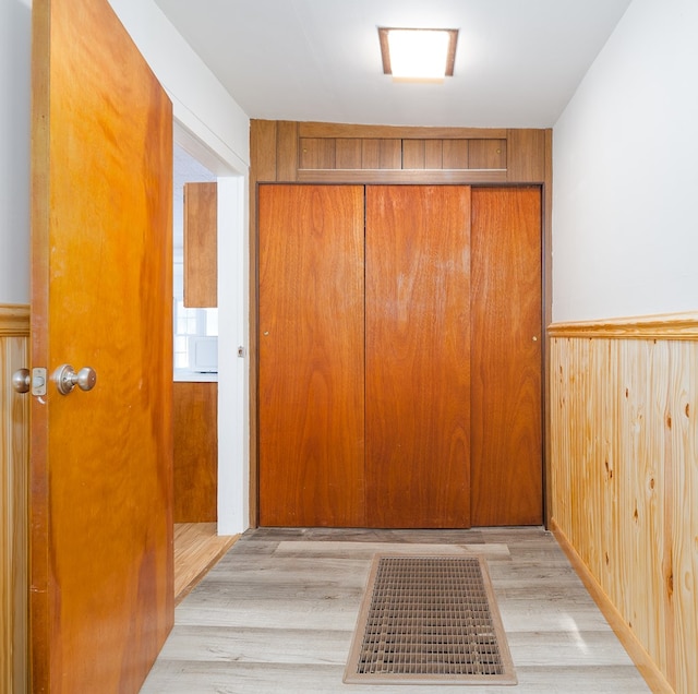 corridor with wood walls and light hardwood / wood-style flooring