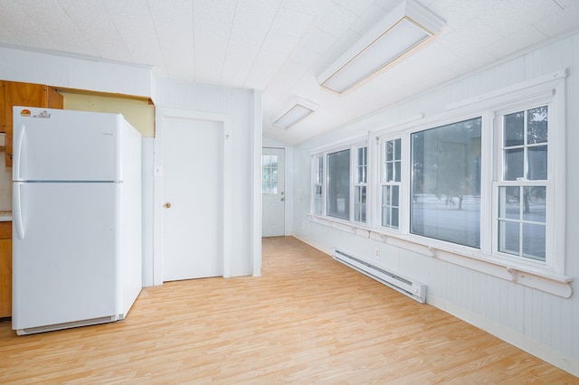 kitchen with a baseboard heating unit, light wood-type flooring, white fridge, and wood walls