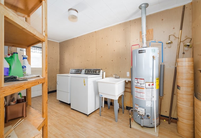 washroom featuring washing machine and dryer, light hardwood / wood-style flooring, and gas water heater