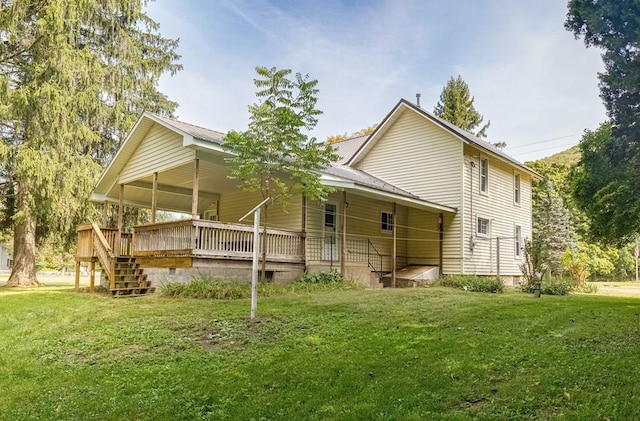 rear view of house featuring a lawn and a wooden deck