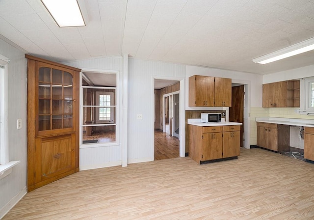 kitchen with wood walls, vaulted ceiling, and light hardwood / wood-style flooring