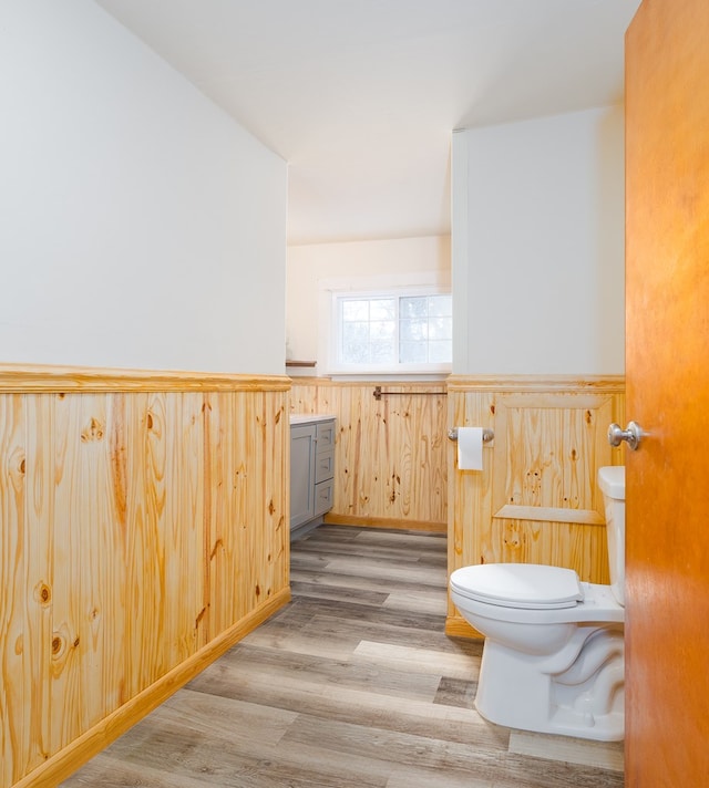 bathroom with toilet, wood walls, and wood-type flooring