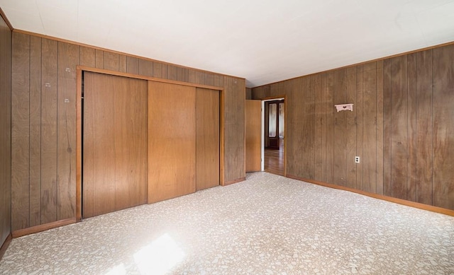 unfurnished bedroom featuring wooden walls and a closet