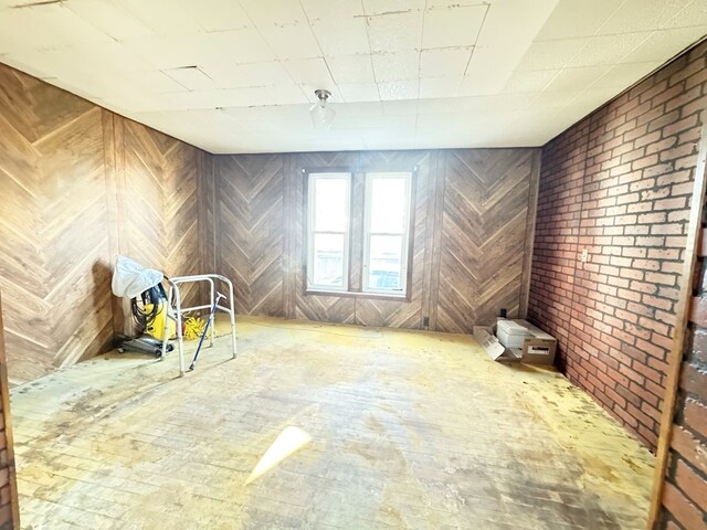 unfurnished room featuring brick wall and wooden walls