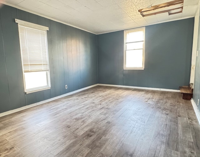 empty room with hardwood / wood-style floors, plenty of natural light, and ornamental molding