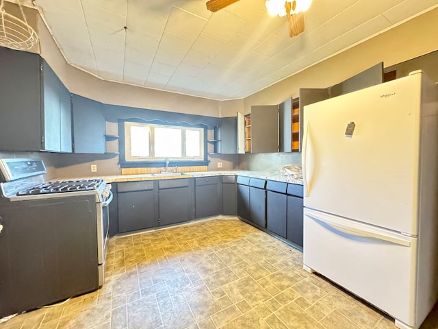 kitchen with gas stove, ceiling fan, sink, white refrigerator, and gray cabinets