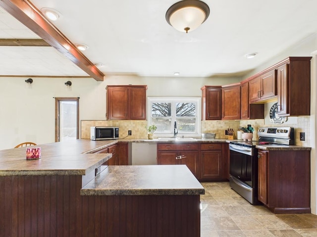 kitchen featuring tasteful backsplash, beam ceiling, a peninsula, stainless steel appliances, and a sink