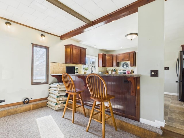 kitchen with tasteful backsplash, baseboards, beamed ceiling, a breakfast bar area, and appliances with stainless steel finishes