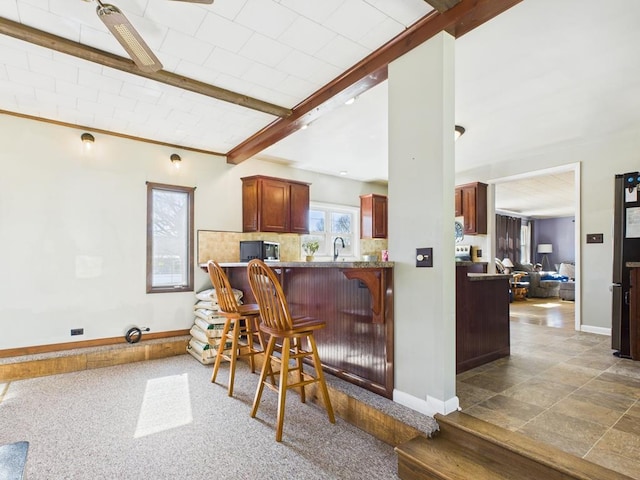 bar featuring a sink, baseboards, beam ceiling, and decorative backsplash