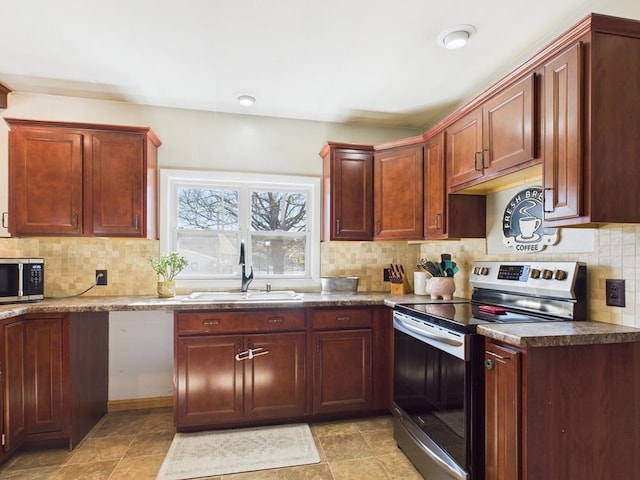 kitchen with a sink, backsplash, dark countertops, stainless steel appliances, and reddish brown cabinets