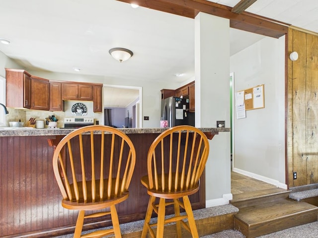 kitchen with stainless steel appliances, baseboards, a peninsula, and a breakfast bar area