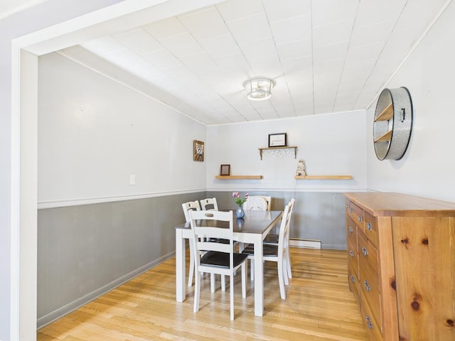 dining space with light wood-type flooring and baseboards