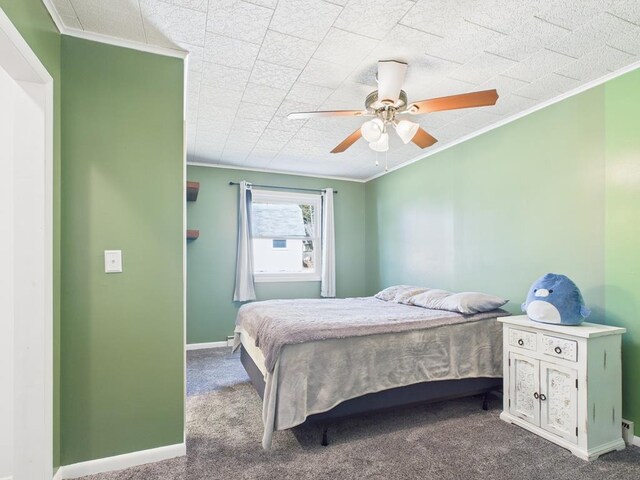 bedroom with ceiling fan, crown molding, baseboards, and dark colored carpet